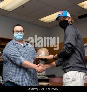 PORT ORCHARD, Washington (28 maggio 2021) – Ryan Reinke, General Foreman, Marine Machinist Shop, Trident Refem Facility Bangor (TRFB) presenta Jansen Viergutz, Senior, South Kitsap High School (SKHS), con un elmetto a SKHS maggio 28. Il personale di leadership di TRFB ha lavorato con i consulenti di SKHS per identificare tre anziani altamente motivati della scuola superiore che hanno un interesse nel lavoro commerciale e li ha intervistati per un potenziale impiego a TRFB. Foto Stock