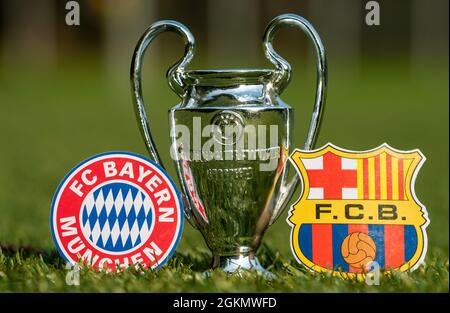 27 agosto 2021 Baviera, Monaco di Baviera. Gli emblemi dei club calcistici FC Barcelona e FC Bayern Monaco e della UEFA Champions League Cup sul prato verde o Foto Stock