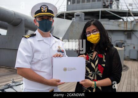 210602-N-HH215-1054 YOKOSUKA, Giappone (2 giugno 2021) – Fang Fang Tseng riceve un certificato di naturalizzazione dal Lt. Andrew Decker, responsabile del dipartimento di assistenza legale assegnato all'Ufficio legale regionale del Pacifico occidentale, durante una cerimonia di naturalizzazione a bordo della nave commemorativa giapponese Mikasa. Durante la cerimonia, sette marinai e civili originari della Costa d’Avorio, delle Filippine, della Sierra Leone e di Taiwan sono diventati cittadini naturalizzati degli Stati Uniti d’America. Foto Stock