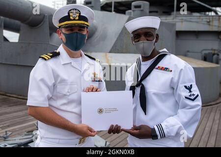 210602-N-HH215-1048 YOKOSUKA, Giappone (2 giugno 2021) – tecnico di attrezzature di supporto per l'aviazione di terza classe Habib Jalloh riceve un certificato di naturalizzazione dal Lt. Andrew Decker, capo del dipartimento di assistenza legale assegnato all'Ufficio di Servizio Legale della Regione Pacifico Occidentale, durante una cerimonia di naturalizzazione a bordo della nave commemorativa giapponese Mikasa. Durante la cerimonia, sette marinai e civili originari della Costa d’Avorio, delle Filippine, della Sierra Leone e di Taiwan sono diventati cittadini naturalizzati degli Stati Uniti d’America. Foto Stock