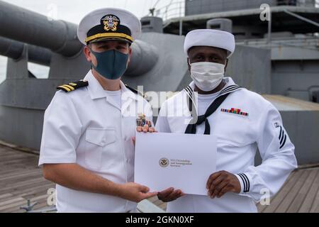 210602-N-HH215-1051 YOKOSUKA, Giappone (2 giugno 2021) – Specialista culinario Seaman Abou Bakary Sidiki Meite riceve un certificato di naturalizzazione dal Lt. Andrew Decker, responsabile del dipartimento di assistenza legale assegnato all'Ufficio di Servizio Legale della Regione Pacifico Occidentale, durante una cerimonia di naturalizzazione a bordo della nave commemorativa giapponese Mikasa. Durante la cerimonia, sette marinai e civili originari della Costa d’Avorio, delle Filippine, della Sierra Leone e di Taiwan sono diventati cittadini naturalizzati degli Stati Uniti d’America. Foto Stock