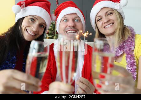 Uomo e donna in babbo natale cappelli bere champagne e tenere scintille nelle loro mani Foto Stock