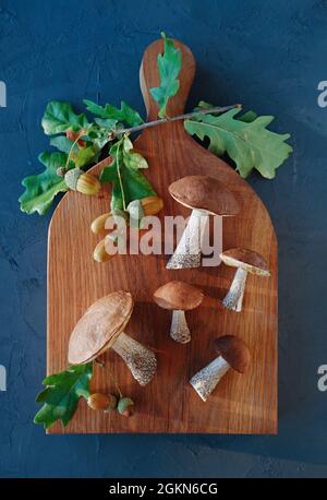 Composizione autunnale. Funghi forestali su sfondo di legno. Disposizione piatta. Vista dall'alto. Ritaglio verticale. Primo piano. Foto Stock
