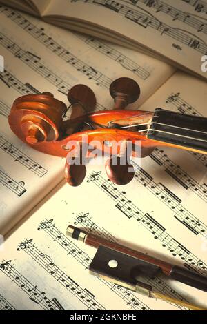 Violino con arco poggiato su spartiti Foto Stock