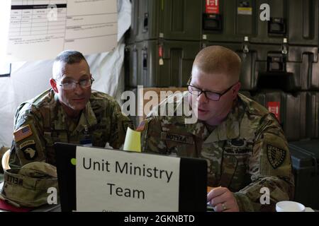 L'Indiana National Guard Lt. Col. Scott Wells, 38° cappellano delle Brigate di sostegno, esamina le procedure dell'unità e riceve un riassunto posteriore da Sgt. Benjamin Motyka, venerdì 4 giugno 2021, a Camp Atterbury, Indiana. I pozzi insieme a Motyka svolgono un ruolo unico nel prossimo esercizio di combattimento in cui forniranno aiuto spirituale ai soldati che ne hanno bisogno. Warfighter esercita soldati di prova in scenari di campo di battaglia virtuale in modo che possano coordinare e comunicare in attività funzionali come comando e controllo, movimento e manovra, intelligenza, processi di targeting, supporto e protezione. Foto Stock