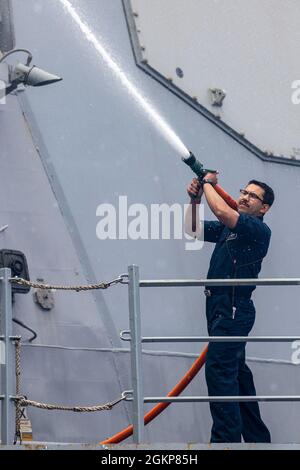 210611-N-QI061-0061 OCEANO ATLANTICO (11 giugno 2021) Cryptologic Technician (Technical) 2nd Class Luis Bonilla, di Lancaster, California, spruzza acqua sulla paratia durante un lavaggio di acqua dolce a bordo del cacciatorpediniere missilistico guidato di classe Arleigh Burke USS Paul Ignatius (DDG 117), 11 giugno 2021. Paul Ignatius opera nell’Oceano Atlantico a sostegno dell’intera gamma di operazioni congiunte e navali della Sesta flotta statunitense, spesso in concerto con partner alleati, congiunti e interagenzie, al fine di promuovere gli interessi nazionali degli Stati Uniti e la sicurezza e la stabilità in Europa e in Africa. Foto Stock