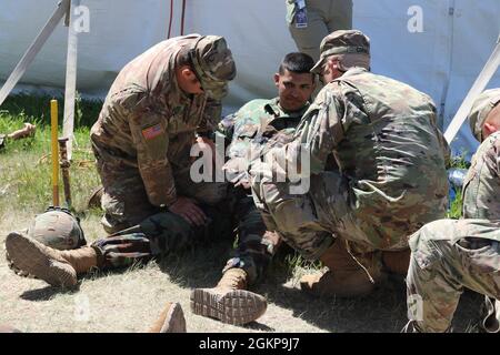 I soldati della Guardia Nazionale dell'Esercito degli Stati Uniti assegnati al secondo Battaglione, il reggimento dell'artiglieria del campo 300 trattano feriti simulati durante uno scenario di addestramento di incidenti di massa al centro di addestramento congiunto di Camp Guernsey, Wyoming, 11 giugno 2021. L'esercizio condotto da 1° osservatore della Divisione Esercito Est, allenatore/allenatore è stato progettato per contribuire a migliorare la capacità dell'unità della Guardia Nazionale del Wyoming di rispondere a tale evento. Foto Stock