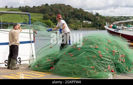 Pescatore che scarica reti da posta monofilamentose da reti da traino. Foto Stock