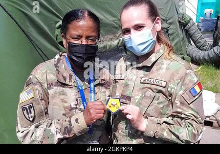 Briga della Riserva dell'Esercito degli Stati Uniti. Il generale Wanda N. Williams, comandante del 7° comando di supporto alla Missione, condivide la sua moneta e una foto con un militare rumeno Multi-National Command Soldier Sud-Est durante una visita alla sede MNC-se per l'esercizio DEFENDER-Europe 21 a Bucarest, Romania, 13 giugno 2021. I soldati del 209° distacco di collegamento digitale, 7° MSC, hanno fornito capacità di collegamento tra il V corpo dell'Esercito degli Stati Uniti, il Joint Force Land Component Command e il rumeno MNC-se. Foto Stock