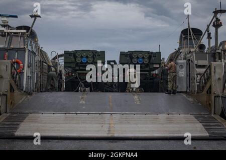 U.S. Marine Corps M142 High Mobility Artillery Rocket System (HIMARS) con batteria Quebec, 3° battaglione, 12° Marines, 31° Marine Expeditionary Unit (MEU), scarica da un'imbarcazione di atterraggio, cuscino d'aria a White Beach, Okinawa, Giappone, 15 giugno 2021. Durante l'esercitazione, Marines ha condotto missioni antincendio simulate con HIMARS imbarcandosi su LCAC per implementare rapidamente la capacità di fuoco di precisione sulla riva attraverso atterraggi anfibi. Il 31° MEU opera a bordo di navi dell'America Amphibious Ready Group nella settima area di attività della flotta per migliorare l'interoperabilità con alleati e partner Foto Stock