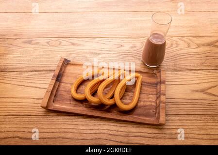 Razione di churros con cioccolato in stile Madrid su tavola di legno Foto Stock