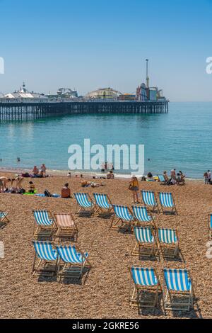 Vista del molo di Brighton Palace e sedie a sdraio a strisce blu e bianche sulla spiaggia, Brighton, East Sussex, Inghilterra, Regno Unito, Europa Foto Stock