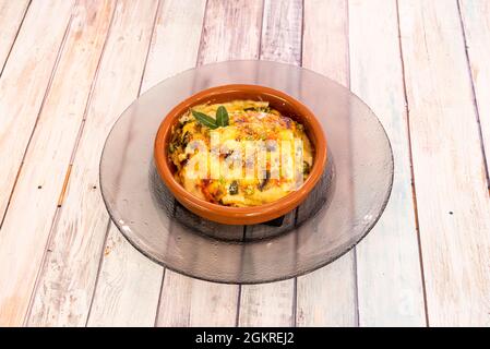 Lasagna vegetariana con gratin di besciamella e fette di pasta italiana in una pentola di argilla su tavola di legno Foto Stock