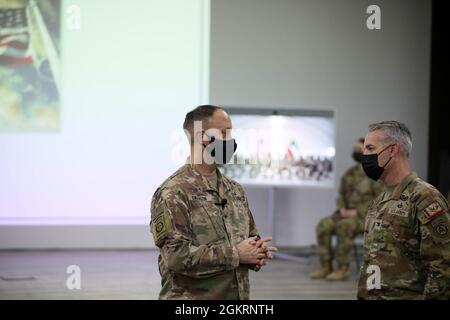 Briga. Il Gen. Justin M. Swanson, comandante generale, 310° comando di supporto di Expeditionary, parla con il col. John Herman, comandante del gruppo di supporto di Area-Kuwait, prima di una cerimonia di riascolto il 23 giugno 2021 a Camp Arifjan, Kuwait. Swanson amministrò il giuramento ai soldati durante la cerimonia. Foto Stock