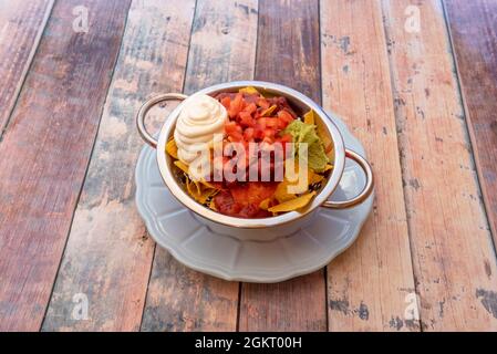 Nachos con fagioli, guacamole e formaggio cremoso squisitamente presentato in una ciotola con bordi dorati Foto Stock