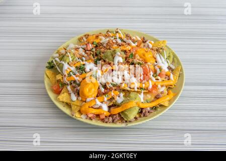 Piatto di nachos con guacamole con un sacco di ingredienti per la bestia su un piatto verde Foto Stock