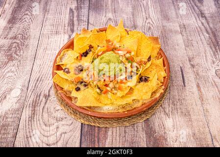 Piatto di argilla con nachos, jalapeños, peperoncino di carne, formaggio, guacamole, tortilla chips, pico de gallo Foto Stock