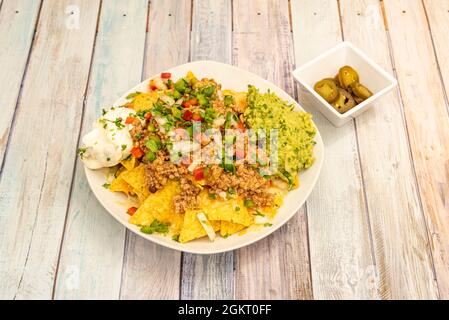 Piatto bianco di nachos con tutto, jalapeños, chili de carne, formaggio, guacamole, tortilla chips, pico de gallo Foto Stock