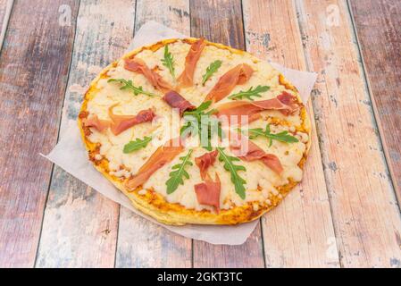 Pizza napoletana con rucola, prosciutto e mozzarella su carta da forno Foto Stock