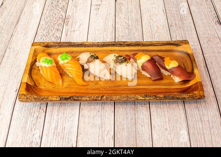 Vassoio di legno con sushi di nigiri assortiti di salmone norvegese, tonno rosso e pesce farfalla con uova di pesce sulla parte superiore Foto Stock