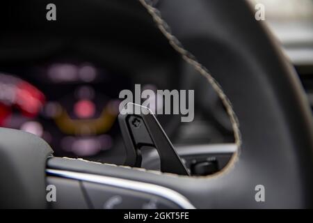 Primo piano della levetta di cambio marcia al volante in una moderna vettura di prima qualità. La levetta di cambio marcia manuale Speedshift si trova sul volante di un'auto e all'interno dell'auto Foto Stock