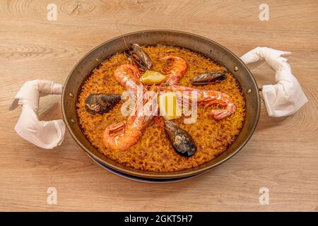 Grande paella di pesce valenciana popolare in estate spagnola servito in una padella con gamberi grandi e appetitosi, fette di limone fresco e super del Foto Stock