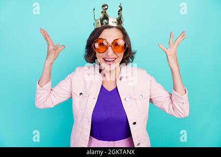 Foto ritratto donna in corona d'oro girone sunglass sorridente mani gesturing ridendo isolato vivido turchese sfondo colore Foto Stock