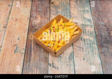 servire di croccanti con pancetta di maiale a dadini, un sacco di formaggio cheddar fuso e erba cipollina tritata in un contenitore di cartone per la consegna a domicilio Foto Stock