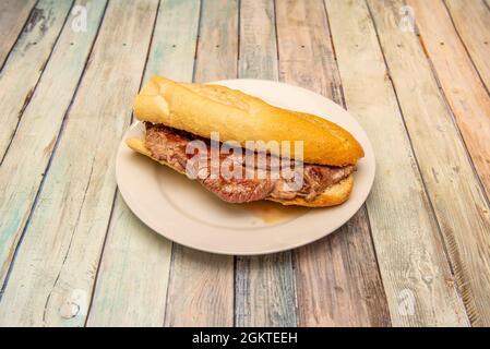 Ottimo panino in stile spagnolo, il pepito, di vitello con una buona bistecca cucinata al momento e servita tra i vari tipi di pane con il suo succo di frutta Foto Stock