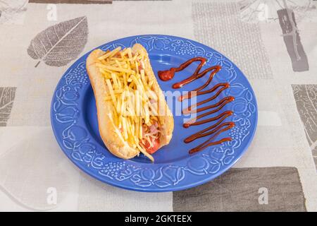 Hot dog con salsiccia con prosciutto e patate paglia con ketchup e senape su piatto di porcellana blu Foto Stock