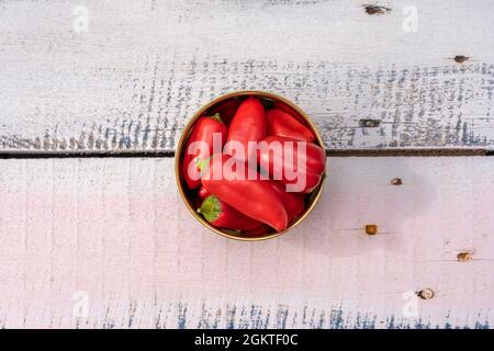 Foto dall'alto di una manciata di piccoli peperoni rossi su legno dipinto a pastello e chiodi metallici Foto Stock