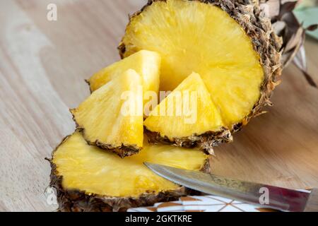 Ananas tagliato a metà con pezzi di ananas e coltello stampigliato sulla lama Foto Stock
