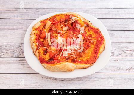 Piccola pizza di crosta di grano sottile con pomodori ciliegini, parmigiano e salsa barbecue su un piatto bianco Foto Stock