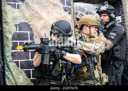 Un Airman del 422° Squadrone delle forze di sicurezza, insieme a funzionari di polizia del dipartimento di polizia del Northamptonshire, conduce un esercizio di risposta attiva dello sparatutto a tre agenzie alla RAF Croughton, Inghilterra, 30 giugno 2021. Gli airman del 422° SFS, insieme agli ufficiali della polizia della NHPD e del Ministero della Difesa, hanno partecipato a molteplici esercizi per migliorare le loro tattiche di ricerca e sequestro, rafforzare i legami locali e ottenere rapporti con i loro compagni di polizia. Foto Stock