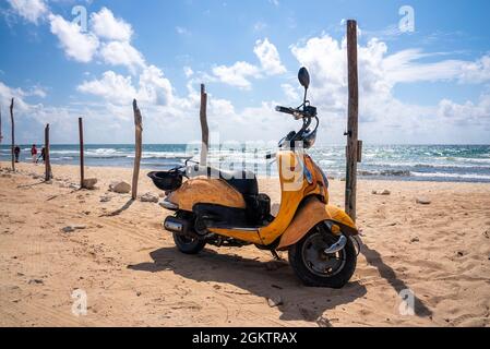 Scooter dal design giallo parcheggiato sulla spiaggia in una giornata di sole Foto Stock