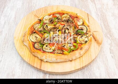 Grande pizza vegana con molti tipi di verdure e funghi con pasta di farina di grano su tavola di legno Foto Stock