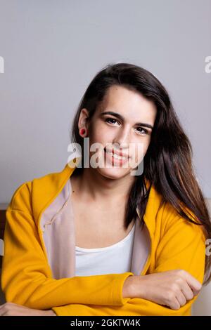 Giovane bella donna ispanica transgender su sfondo grigio Foto Stock