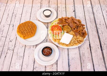 Menu kebab con formaggio fresco, falafel, carne di agnello, riso basmati e pomodoro e insalata di lattuga iceberg con pane pita e salse Foto Stock