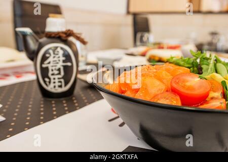 Ciotola di poke di salmone con pomodoro ciliegia e lattuga assortita servita in un ristorante cinese Foto Stock