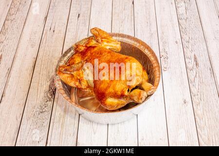 Pollo intero arrosto in contenitore di alluminio per la consegna a domicilio su tavola bianca Foto Stock