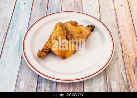 Pollo cotto a metà su un piatto bianco con bordo rosso Foto Stock