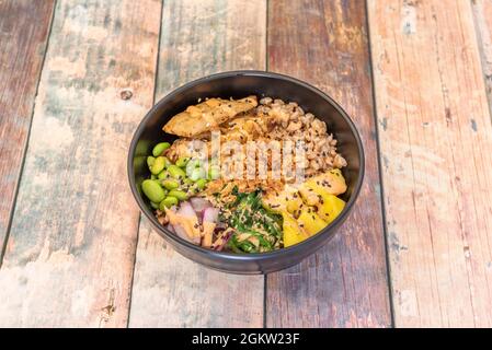 Ciotola di poke fagioli di edamame vegani, bulgur cotto, cipolla croccante, tofu tritato, mango, cipolla rossa e alghe wakame Foto Stock