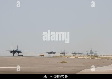 Un KC-10 Extender dal 908th Expeditionary Air Refeling Squadron e diversi F-15E Sciopero Eagle assegnati al 494th Expeditionary Fighter Squadron prepararsi per il decollo 5 luglio 2021 dalla base aerea di al Dhafra, Emirati Arabi Uniti. Con l'assistenza dell'aeromobile KC-10 Extender, gli F-15s e le relative attrezzature e equipaggio sono in grado di tornare alla loro stazione di casa in un'unica missione consolidata, massimizzando l'utilizzo di tempo e risorse. Foto Stock