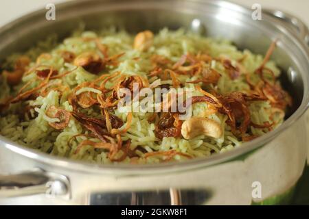 Biriyani verde servito in una pentola d'acciaio. Si compone di riso basmati bollente con pasta di chutney di coriandolo verde e spezie e poi si stratificato con il curry Foto Stock