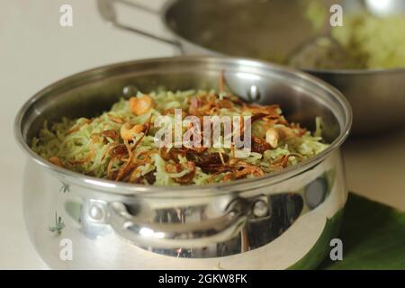 Biriyani verde servito in una pentola d'acciaio. Si compone di riso basmati bollente con pasta di chutney di coriandolo verde e spezie e poi si stratificato con il curry Foto Stock