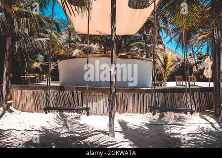 Appendere posti a sedere vuoti swing sulla sabbia presso il resort sulla spiaggia in una giornata di sole Foto Stock