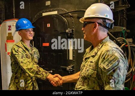 210708-N-OA516-0098 SAN DIEGO (8 luglio 2021) Vice ADM. Roy Kitchener, Comandante, Naval Surface Force, U.S. Pacific Fleet, destra, Presenta una moneta di sfida a Airman William Greenlee, un veliero assegnato alla nave d'assalto anfibio USS Boxer (LHD 4) di classe Wasp. Durante la visita alla nave, Kitchener ha valutato l'attuale stato di preparazione di Boxer e ha parlato con i marinai. Foto Stock