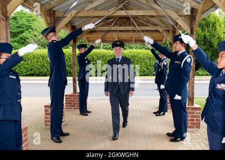 Royal Air Force Sqn. LDR. Clive Wood, Center, RAF Alconbury e RAF Molesworth RAF Commander, cammina attraverso un arco di sciabola tenuto da Air Force Junior ROTC cadets durante il 2021 Wing Commander Annual Reception alla Royal Air Force Alconbury, Inghilterra, 9 luglio 2021. I leader civici di tutti i distretti di Cambridgeshire, Northamptonshire orientale e Fenland hanno visitato con i membri del 423rd Air base Group, dove hanno avuto l'opportunità di costruire relazioni con i loro partner statunitensi e di saperne di più sulla 501st Combat Support Wing mission. Foto Stock