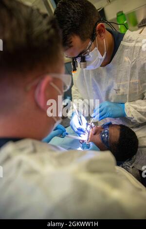 Aviation Boatswain's Mate (Handling) Airman Andrew Henderson, centro, da New Lebanon, New York, assegnato a USS Gerald R. Ford's (CVN 78) reparto aereo, subisce una procedura dentale da, Lt. David Anguiano, destra, da Austin, Texas, E l'ospedale Corpsman 2a classe Aaron Van Dyke, di Mogadore, Ohio, assegnato al dipartimento medico della Ford, 13 luglio 2021. Ford è in corso nell'Oceano Atlantico che conduce i processi di Shock Full Ship. La Marina degli Stati Uniti conduce prove d'urto di nuovi progetti di navi usando esplosivi vivi per confermare che le nostre navi da guerra possono continuare a soddisfare i requisiti di missione impegnativi sotto Foto Stock