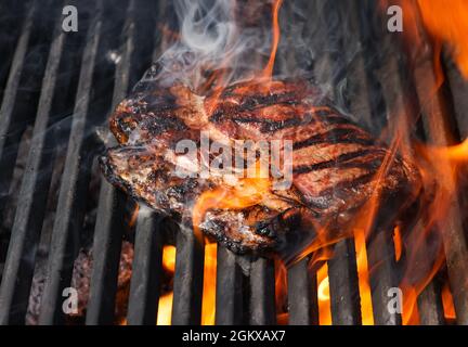 Primo piano con bistecche di manzo al ribeye al fuoco aperto con griglia in metallo ghisa, vista ad alta angolazione Foto Stock